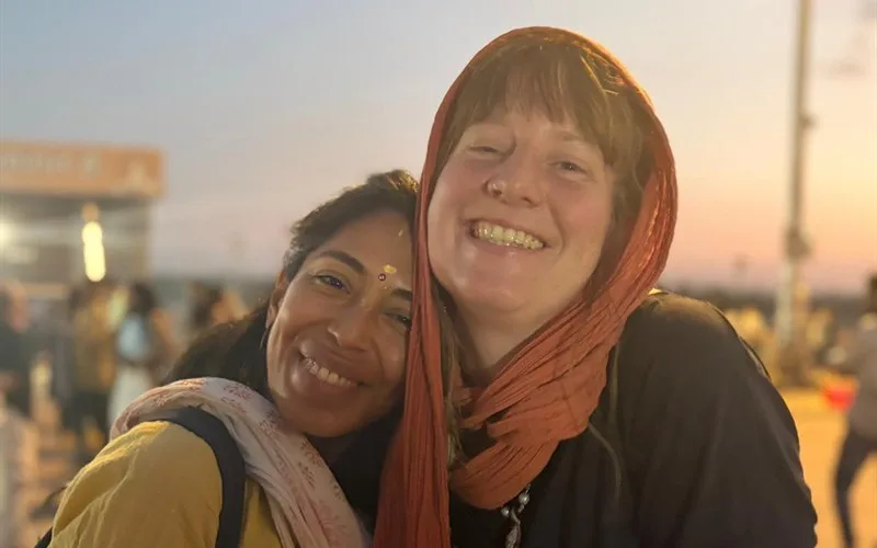 Two friends sharing a smile at the ghat at sunset