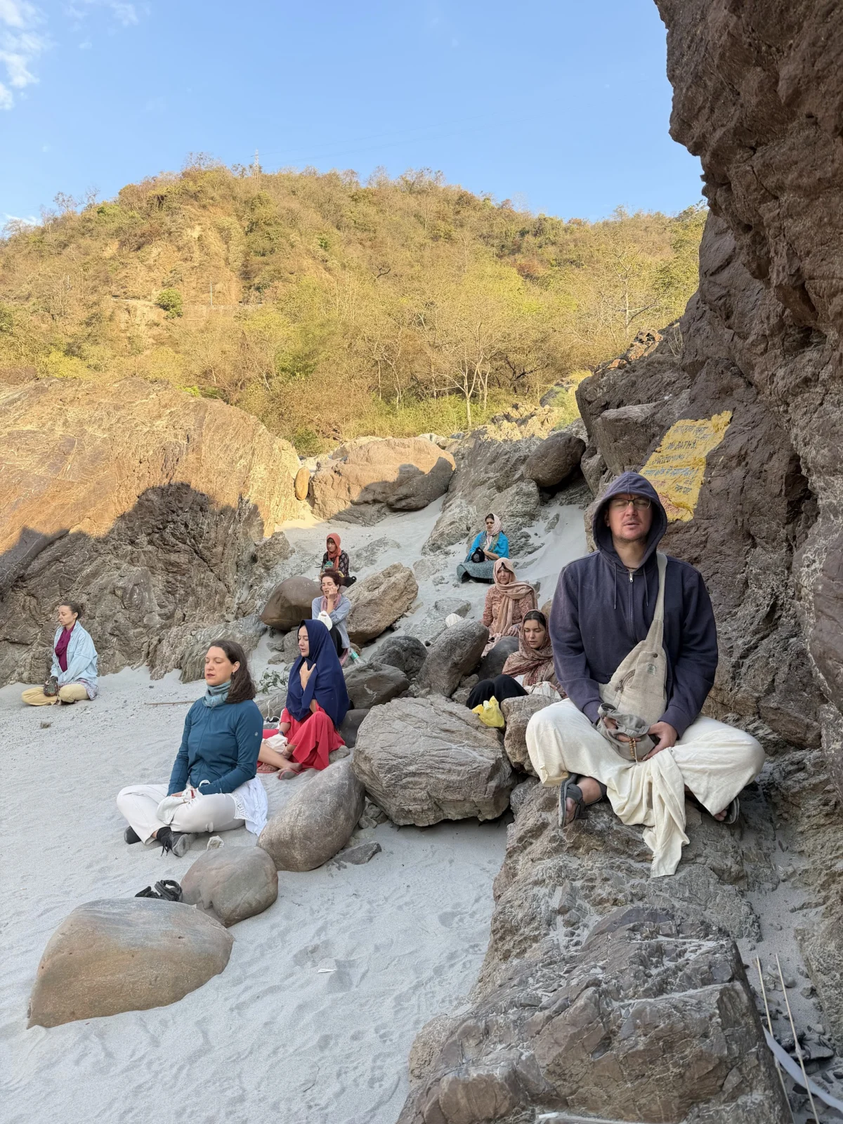 Participants in quiet meditation on the sandy banks of the Ganga near Rishikesh